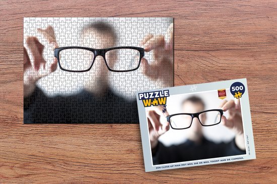 MuchoWow Puzzel Een close-up man met bril die de bril toont aan de camera. - Legpuzzel - Puzzel 500 stukjes