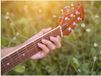 Merkloos / Sans marque Poster - Close-up van Vrouwenhand op Bruine Gitaar in Bloemenveld - 100x75 cm