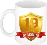 Bellatio Decorations Leeftijd cadeau koffiemok - 19 jaar - Gefeliciteerd - Gouden schild en wimpel - jubileum - verjaardag - beker - 300 ml - wit
